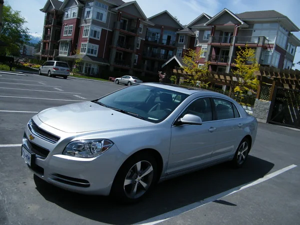 Chevy Malibu parked in a lot in front of an apartment complex