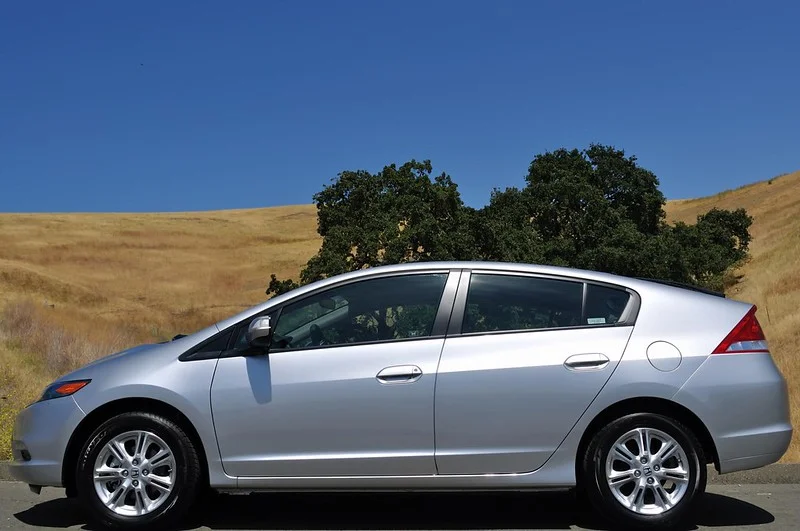 Silver Honda Insight parked in front of a field