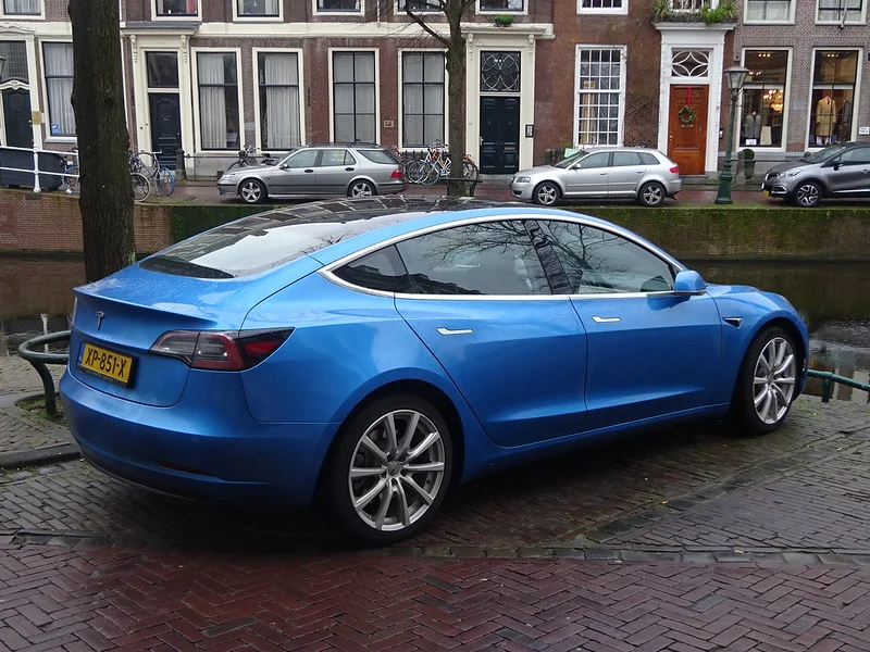 Blue Tesla Model 3 parked on a cobblestone street