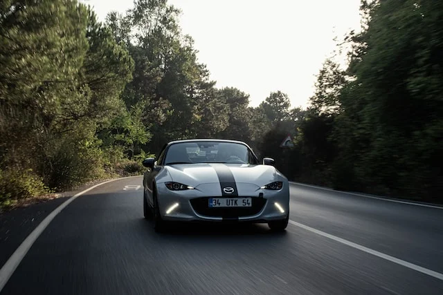 white Miata in the woods