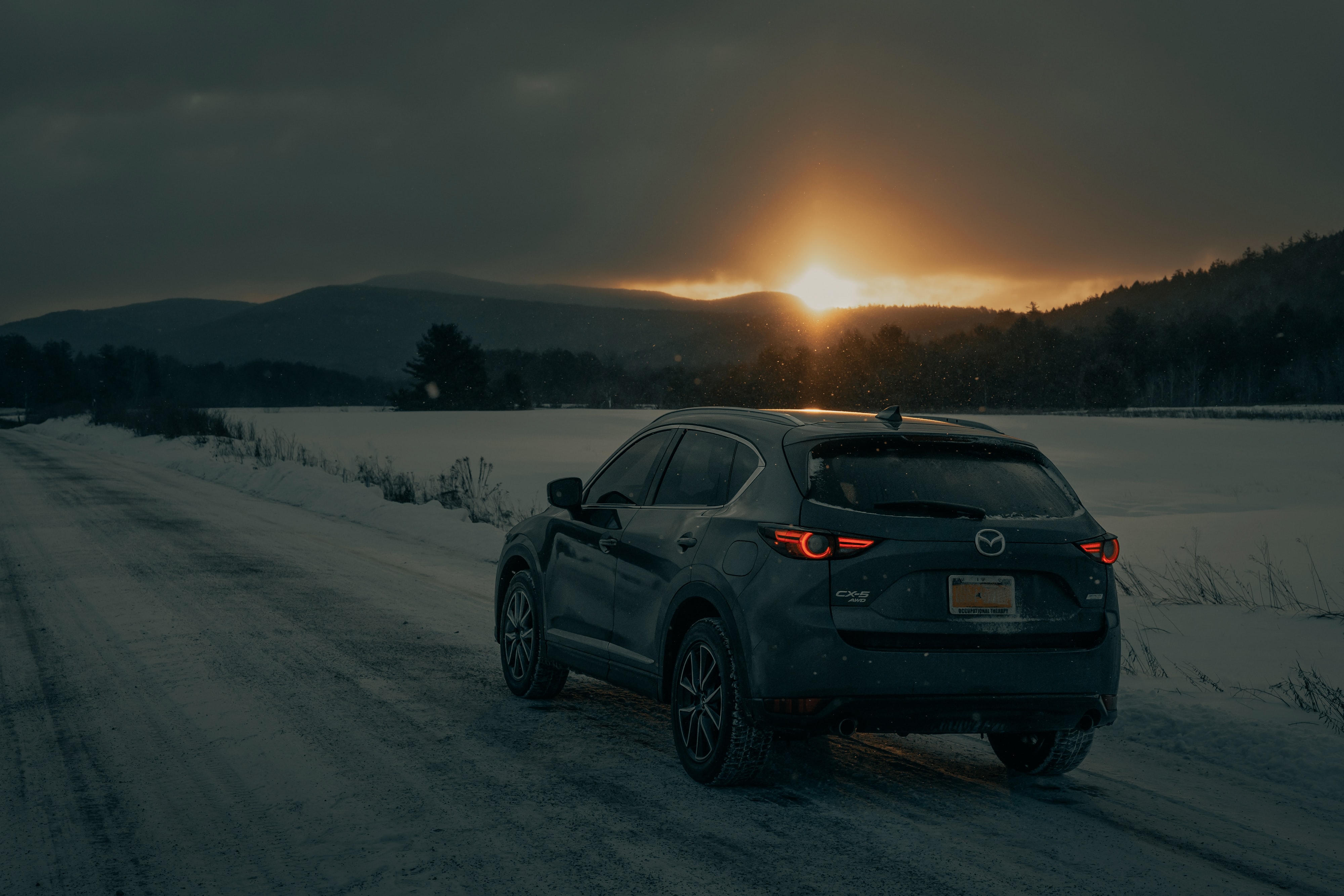 Car driving through the snow at sunset