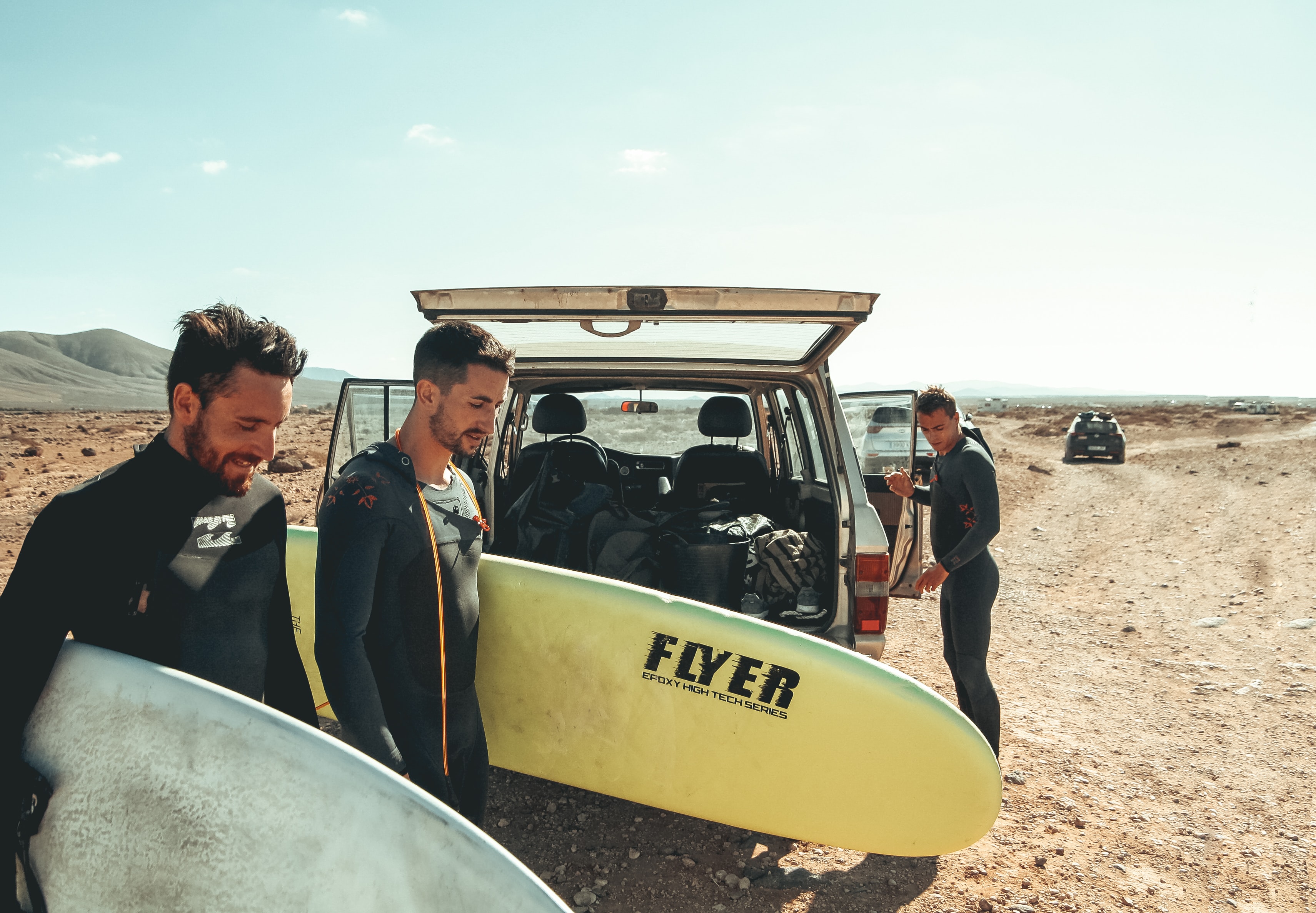 Surfers grabbing boards from a car