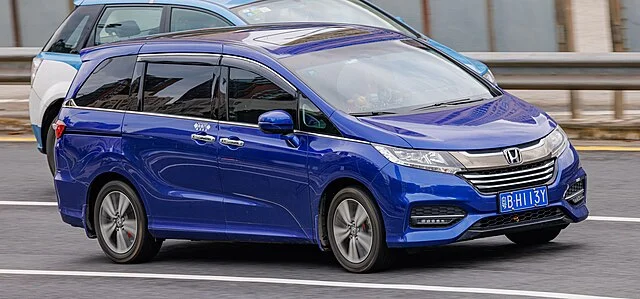Blue Honda Odyssey driving on a road