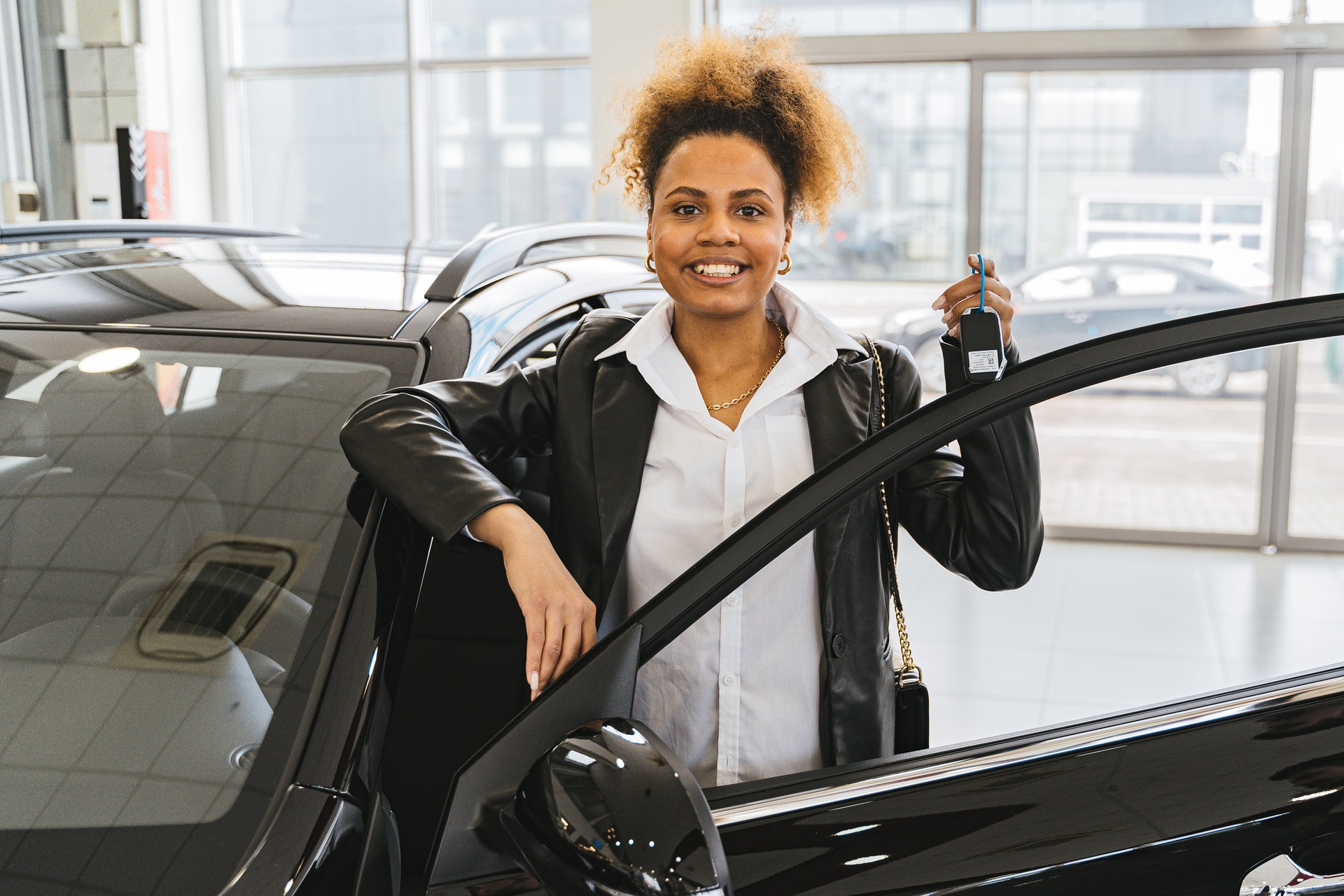 Photo of woman at car dealership with new car