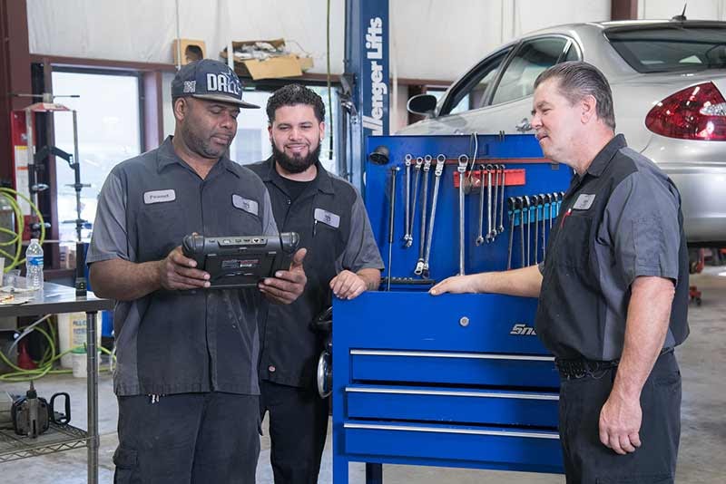 Photo of mechanics and customer inside used car pre-purchase station inspection bay